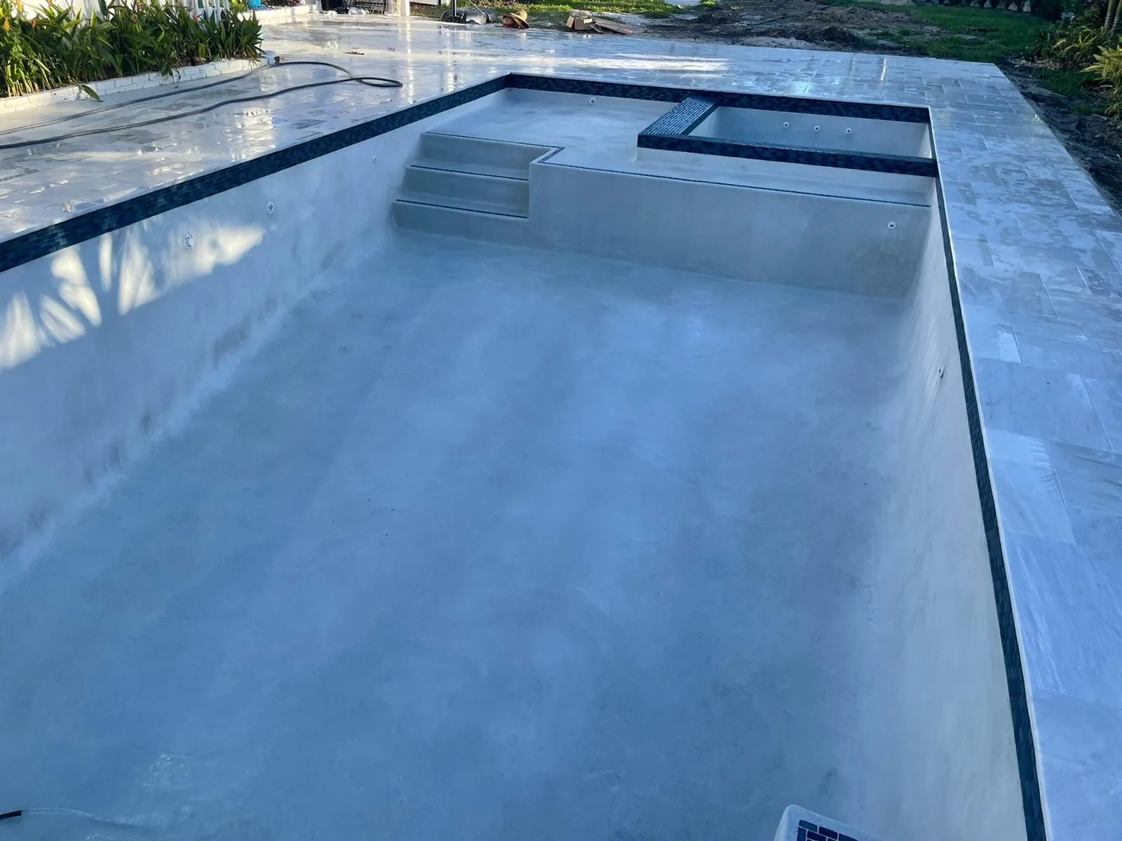Rectangular pool with a raised spa and a fresh interior, edged in dark waterline tile.