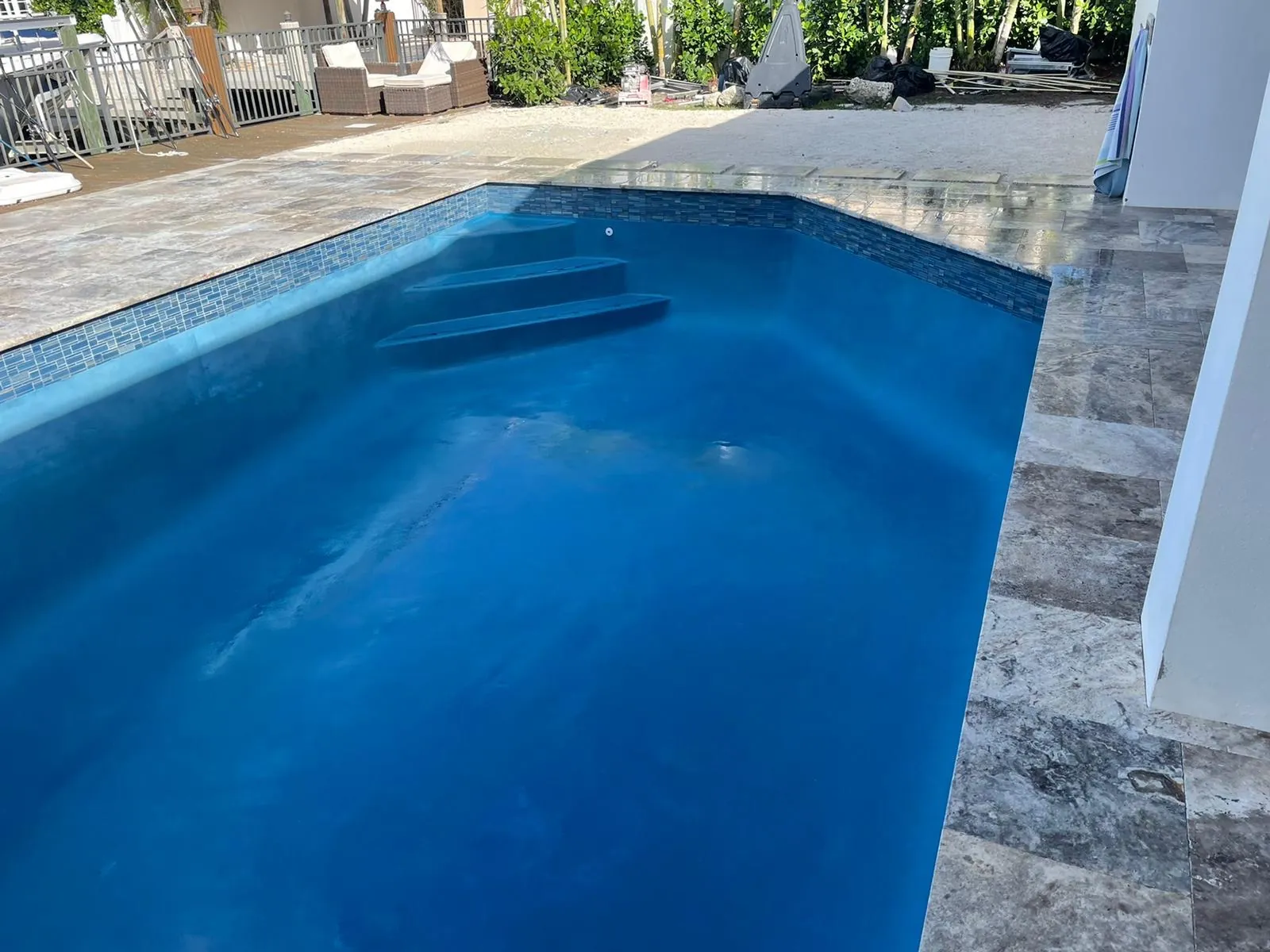Rectangular pool with a deep blue finish, built-in steps, and stone coping.