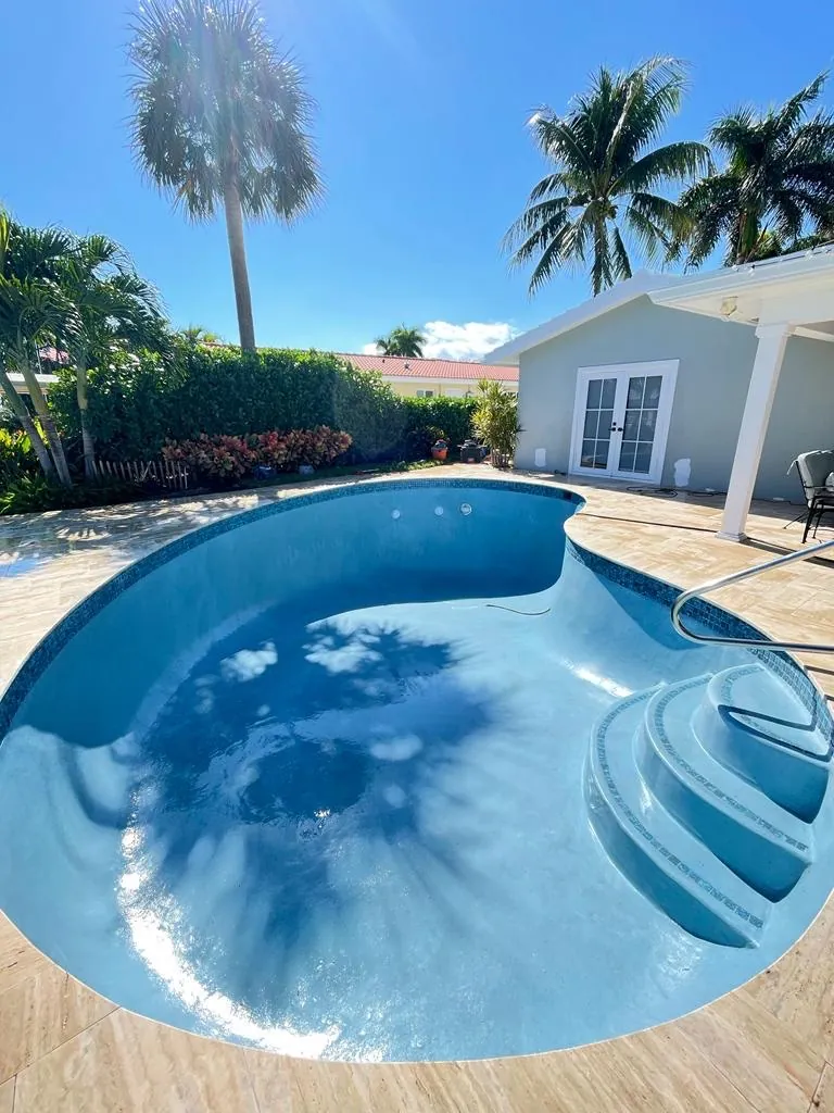Kidney-shaped pool with curved steps and a bright blue finish.
