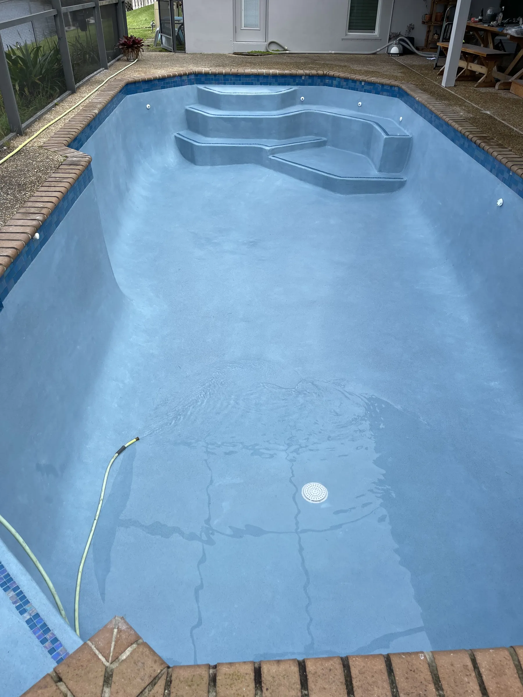 Drained pool with a light blue interior finish and corner steps.