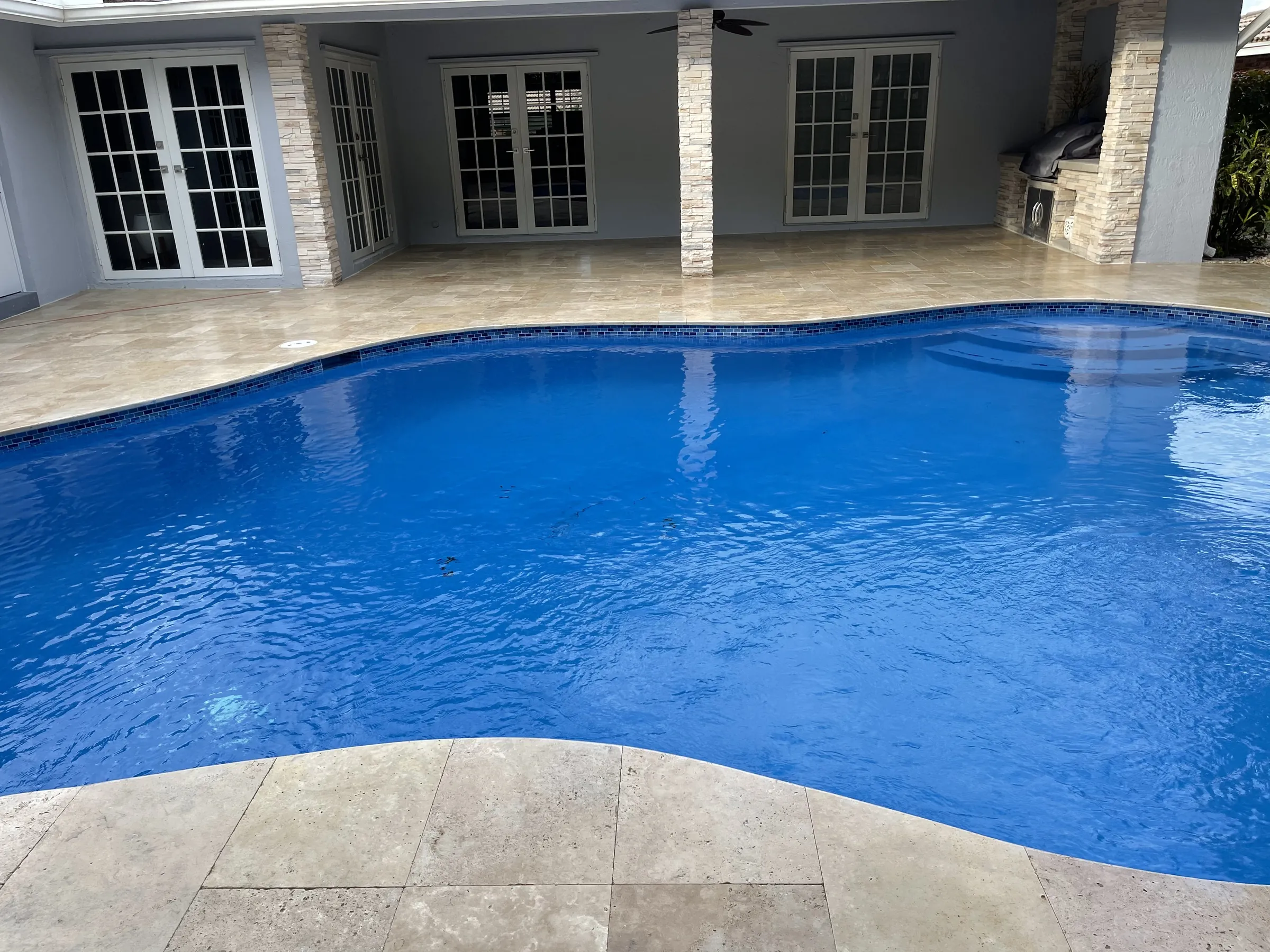 Deep blue water against a pale stone deck, just outside the French doors.