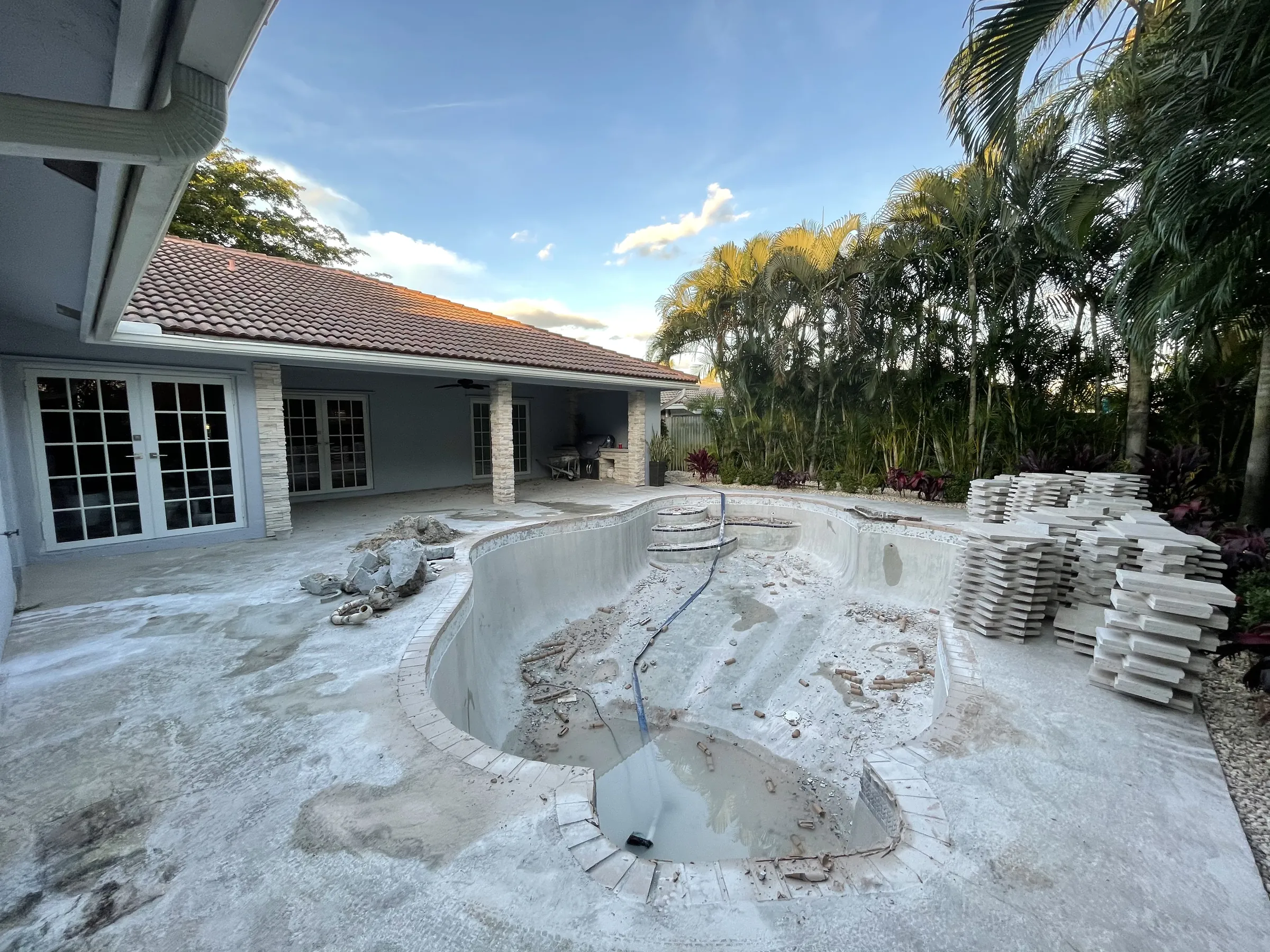 Before: the pool shell opened up, with curved steps and construction debris.