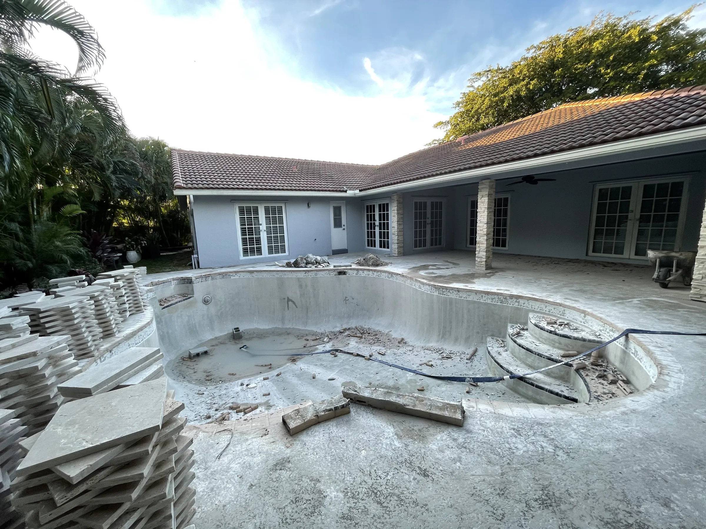 In progress: a stripped pool shell and stacked pavers ready for the new deck.