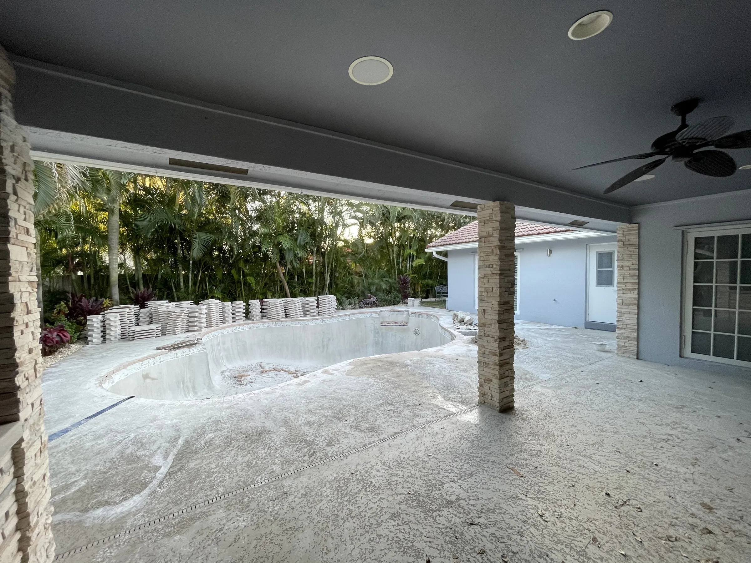 In progress: the pool shell seen from the covered patio before the new deck went in.