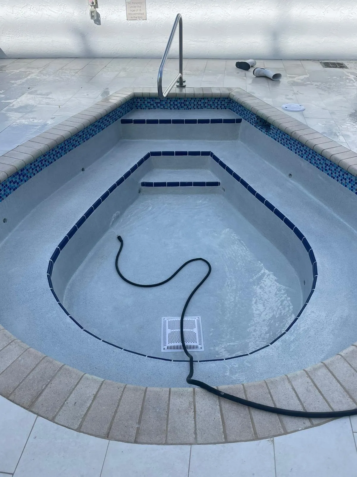 Teardrop-shaped spa and pool steps framed by a wood-look border.