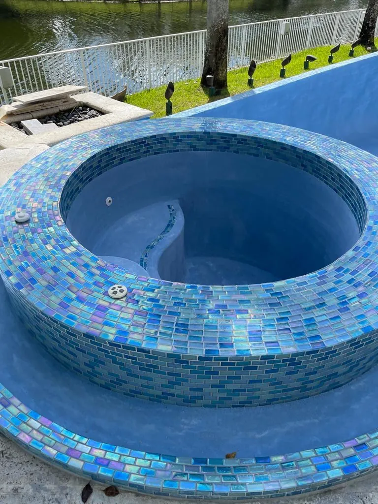 Raised round spa wrapped in blue-green glass mosaic tile.