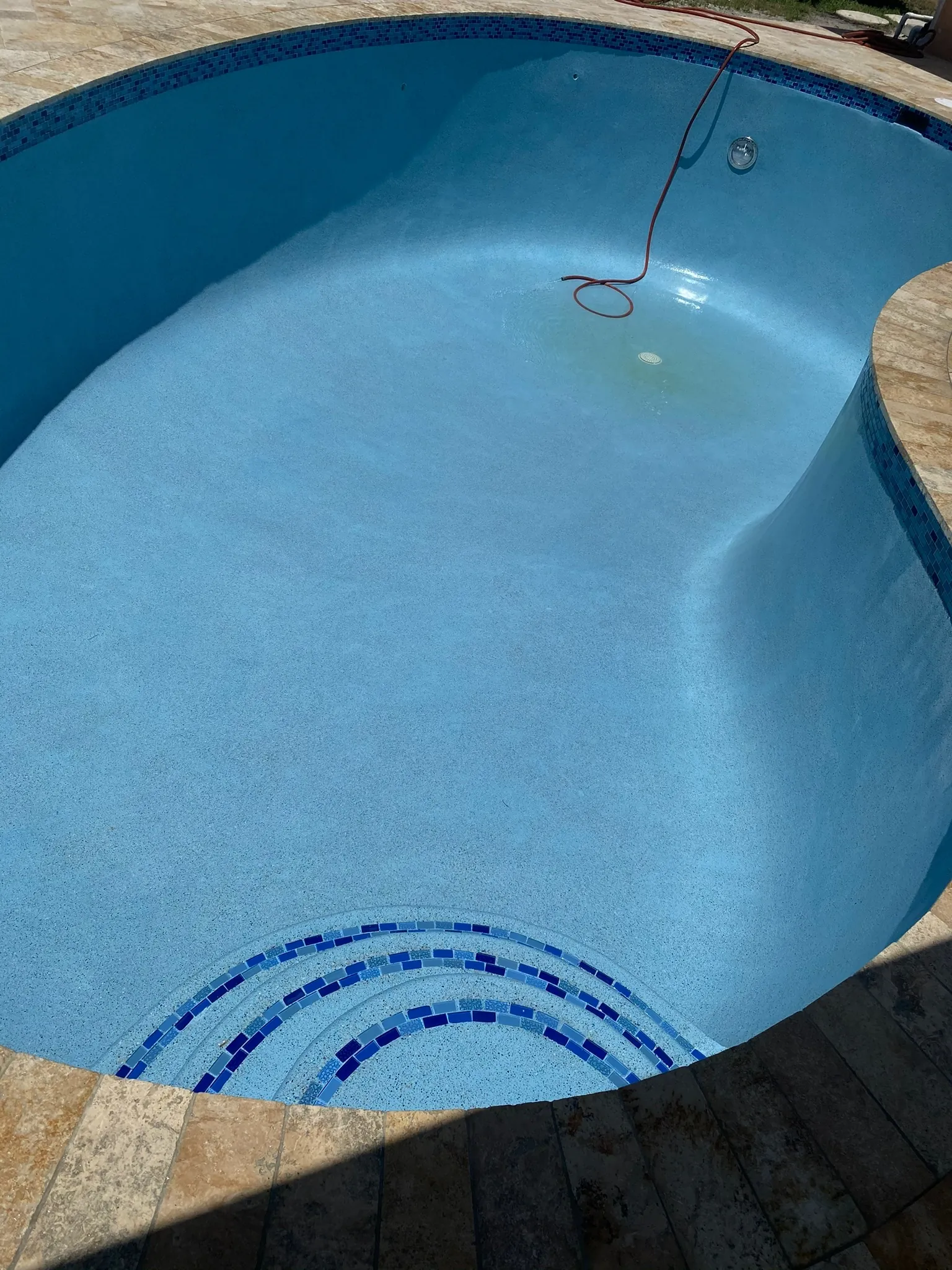Oval pool with a blue mosaic tile pattern across the steps.