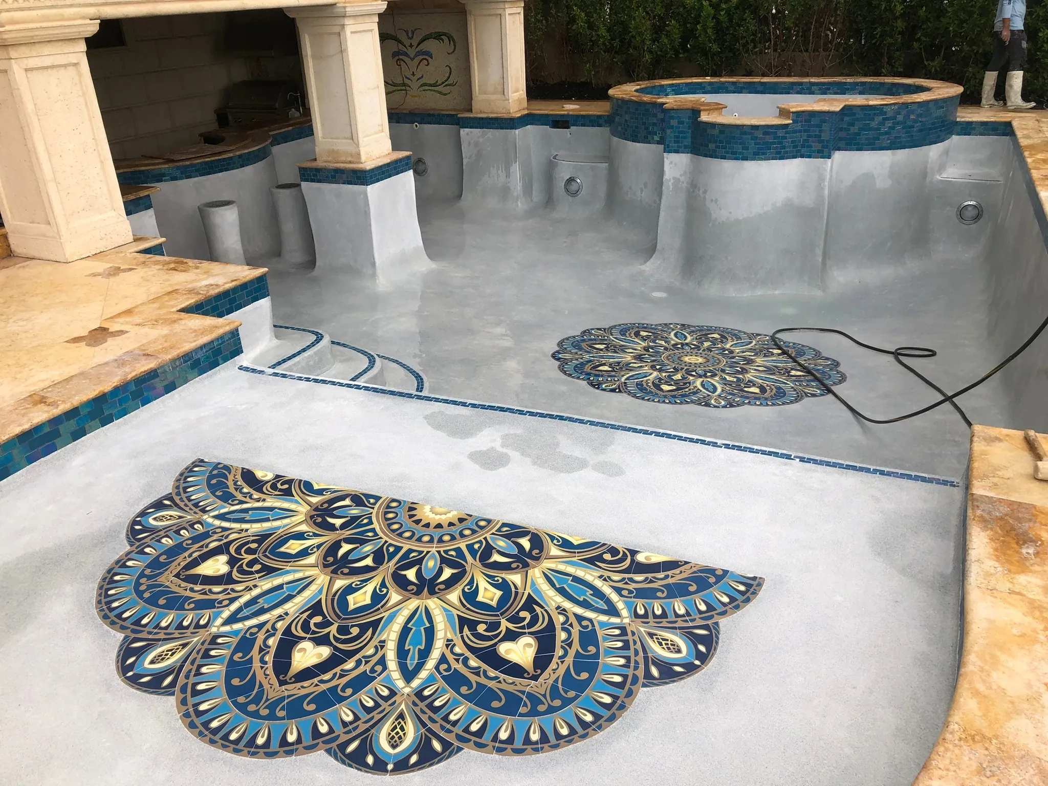 Large decorative mosaic medallions set into pool steps and floor.
